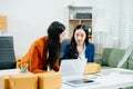 Two business women collaborate in a modern office, working on e-commerce packaging and startup ideas with laptops, teamwork Royalty Free Stock Photo