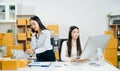 Two business women collaborate in a modern office, working on e-commerce packaging and startup ideas with laptops, teamwork Royalty Free Stock Photo