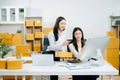 Two business women collaborate in a modern office, working on e-commerce packaging and startup ideas with laptops, teamwork Royalty Free Stock Photo