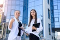 Two business women signing contract outdoors before building of big office center Royalty Free Stock Photo