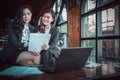 Two business woman sit on sofa and see document on hand and computer on the table