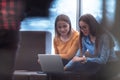 Two business women sitingt in a modern coworking space on a break from work and relax using a laptop. Selective focus Royalty Free Stock Photo