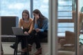 Two business women sitingt in a modern coworking space on a break from work and relax using a laptop. Selective focus Royalty Free Stock Photo