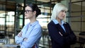 Two business women standing back to back looking angrily, career competition Royalty Free Stock Photo