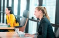 Two Business women working happily in modern business office, One woman is laughing and working on laptop computer. For Happy Royalty Free Stock Photo