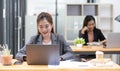 Two business women are working on a notebook computer, holding a pen and looking at the screen in office. Royalty Free Stock Photo