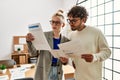 Two business workers concentrated reading paperwork standing at the office