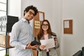 Two business workers smiling happy reading paperwork and using touchpad at the office Royalty Free Stock Photo