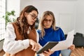 Two business workers woman reading paperwork using touchpad at the office Royalty Free Stock Photo