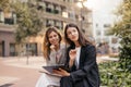 Two business young caucasian female colleagues are using tablet sitting outdoors. Royalty Free Stock Photo