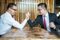 Two businessman expressed a serious expression and fighting by used arm wrestling on wood table.