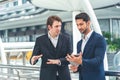 Two businessman holding a tablet seriously having a work discussion outdoor. Young businessman asking for manger opinion