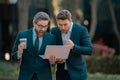 Two businessman using laptop outdoor. Businessmen discussing using lapto on coffee break outdoor. Two business people Royalty Free Stock Photo