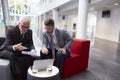 Two Businessmen Discuss Document In Lobby Of Modern Office Royalty Free Stock Photo