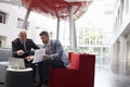 Two Businessmen Discuss Document In Lobby Of Modern Office Royalty Free Stock Photo