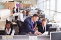 Two businessmen discussing work in a busy, open plan office Royalty Free Stock Photo