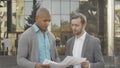 Two businessmen examining documents in front of business building