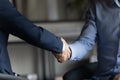 Two businessmen in formal suits shaking hands after successful negotiations