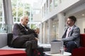 Two Businessmen Meeting In Lobby Area Of Modern Office Royalty Free Stock Photo