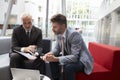 Two Businessmen Meeting In Lobby Area Of Modern Office