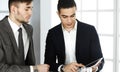 Two businessmen or partners working with tablet computer at the desk in modern office. Headshot of arab male Royalty Free Stock Photo