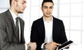 Two businessmen or partners working with tablet computer at the desk in modern office. Headshot of arab male Royalty Free Stock Photo