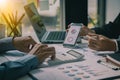 Two businessmen with pens pointing at financial market analysis charts using laptops while analyzing documents in hand with financ Royalty Free Stock Photo