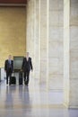 Two Businessmen Pulling Luggage In Airport Lobby