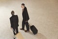 Two Businessmen Pulling Suitcases In Lobby