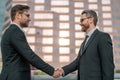 Two businessmen shaking hands on city street. Business men in suit shaking hands outdoors. Handshake between two Royalty Free Stock Photo