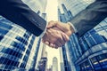 Two businessmen shaking hands in front of office buildings. Close-up of handshake, corporate agreement concept with Royalty Free Stock Photo