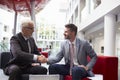 Two Businessmen Shaking Hands In Lobby Of Modern Office Royalty Free Stock Photo