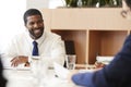 Two Businessmen Sitting Around Table Meeting In Modern Open Plan Office Royalty Free Stock Photo