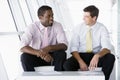 Two businessmen sitting in office lobby talking Royalty Free Stock Photo