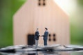 Two businessmen standing in the coin and shake hand and deal business on selling house with blurred background Royalty Free Stock Photo