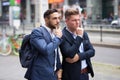 Two businessmen standing in street and looking at something