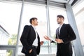 Two businessmen with tablet and mobile phone talking in office Royalty Free Stock Photo