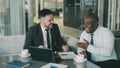 Two businessmen talking ang laughing in modern cafe. Business colleagues having fun and joking looking at laptop Royalty Free Stock Photo