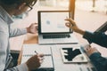 Two businessmen are together analyzing the financial data graph and pointing to the laptop computer screen Royalty Free Stock Photo