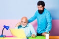 Two businessmen using computer together discussing news or movie. Old and young men looking at laptop screen watching