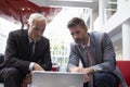 Two Businessmen Using Laptop In Lobby Area Of Modern Office Royalty Free Stock Photo