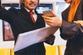 Two businesspeople reading and discussing news. One holding newspaper while the other holding modern news from phone. Royalty Free Stock Photo