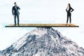 Two businesspeople standing on wooden board on mountain top Royalty Free Stock Photo