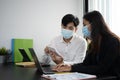 Two businesspeople wearing protective mask using calculator and working together in the office. Royalty Free Stock Photo