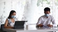 Two businesspeople wearing protective mask working and discussing project together in office. Royalty Free Stock Photo