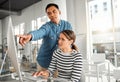 Two businesspeople working on a desktop computer together at work. Young asian male manager training a new employee in Royalty Free Stock Photo