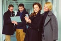 Two businesswoman looking smart phone in lobby with colleagues at background Royalty Free Stock Photo