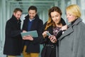 Two businesswoman looking smart phone in lobby with colleagues at background Royalty Free Stock Photo