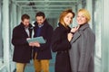 Two businesswoman looking on you in lobby with colleagues at background Royalty Free Stock Photo