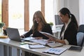 Two businesswoman reviewing financial documents together.